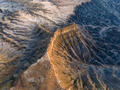Utah sandstone escarpment dividing golden mesa and blue shale badlands.