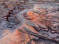 Warm evening light reveals swirling pink and cream sediment layers in Utah’s painted badlands.