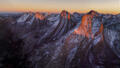 Snow-dusted Colorado peaks blaze in fiery alpenglow at sunset in the Rocky Mountains.