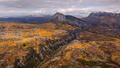 Golden aspen hills surround a rugged granite peak in a sweeping Colorado autumn panorama.