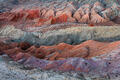 Red, coral, cream, and blue bentonite hills layered in Utah badlands.