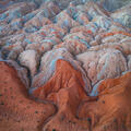 Red and cream badlands mounds with blue mineral streaks in Utah.