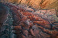 Flowing red and ivory shale sweep through Utah’s painted badlands in a dramatic aerial study of erosion and light.