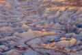 Winding desert wash through pale clay hills in Utah badlands.