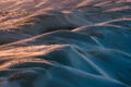 An elegant aerial view of rolling sand dunes shaped into soft abstract forms by wind and light.