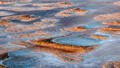 An abstract aerial view of isolated landforms scattered across a dry Australian lake bed in soft natural color.