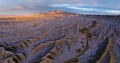 Endless Utah badlands unfold toward a mountain range beneath layered evening skies.