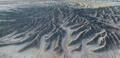 Aerial view of blue-gray badlands ridges and branching washes in Utah.