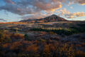 A Colorado mountain rises above layered autumn valleys under soft, shifting light.