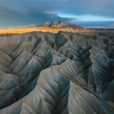 Blue-gray Utah badlands rise like stone cathedrals beneath distant mountains and shifting light.