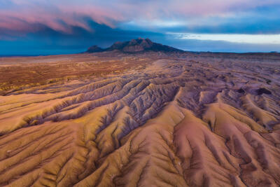 Golden ridges ripple toward distant mountains beneath vibrant Utah twilight skies.