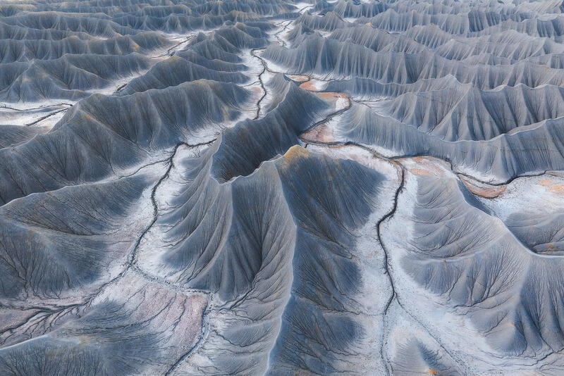 Gray shale ridges and winding erosion channels in Utah badlands.