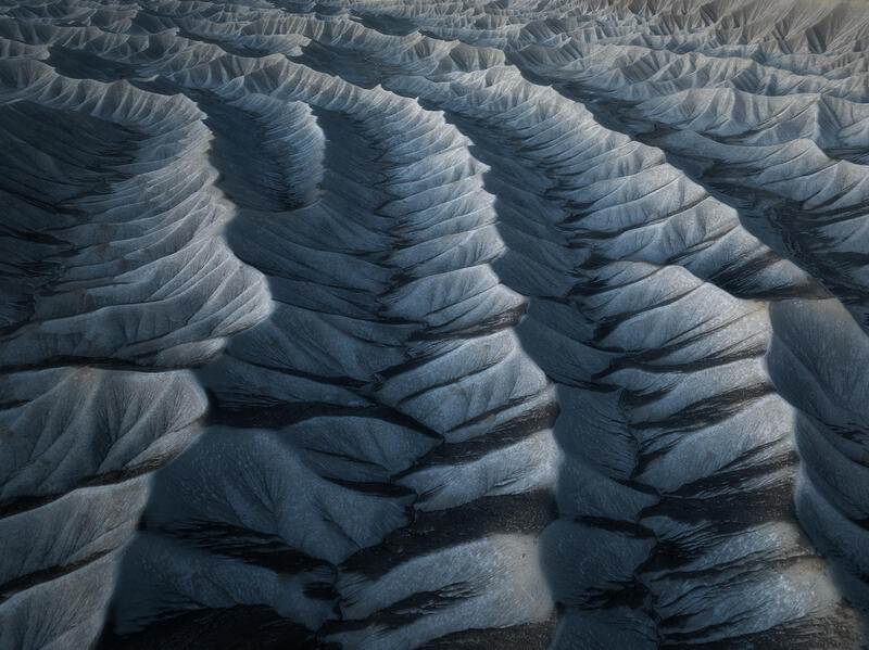 Shadowed blue-gray desert ridges form a striking rhythmic pattern across Utah’s sculpted badlands.