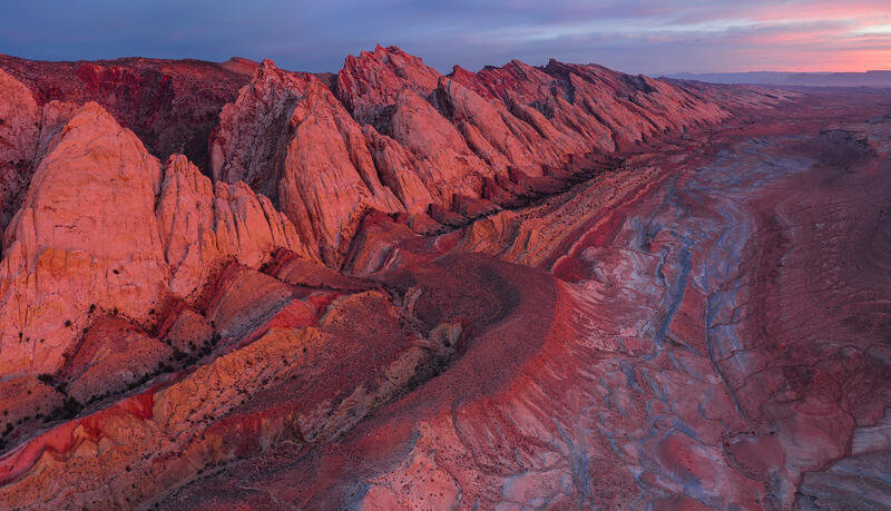 Dawn light sets the San Rafael Swell’s towering sandstone fins ablaze in crimson tones.