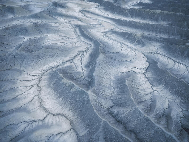 Silver-blue clay ridges ripple in flowing erosion patterns across Utah’s badlands.