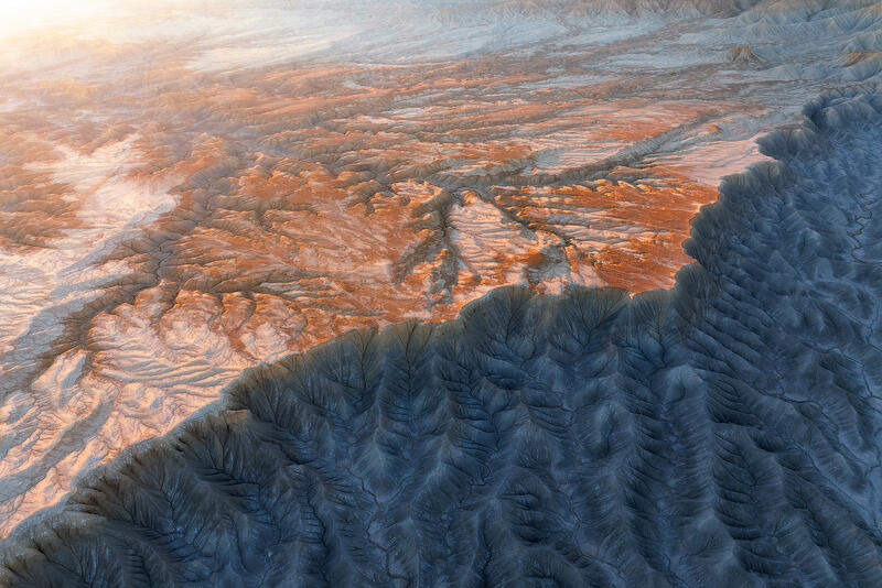 Golden mesa above indigo shale ridges in Utah badlands.
