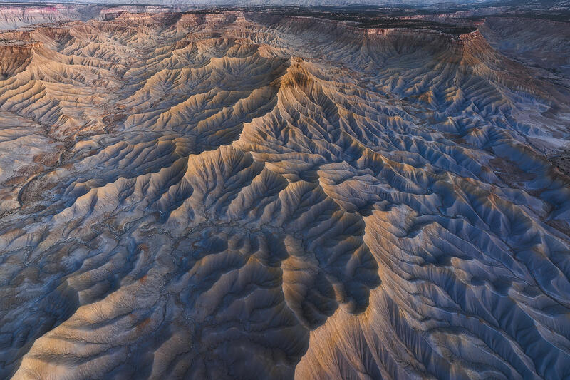 Golden hour light illuminating sweeping ridges in Utah badlands.