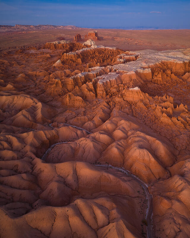 Rolling desert domes lead toward glowing canyon walls in Utah’s vast wilderness.