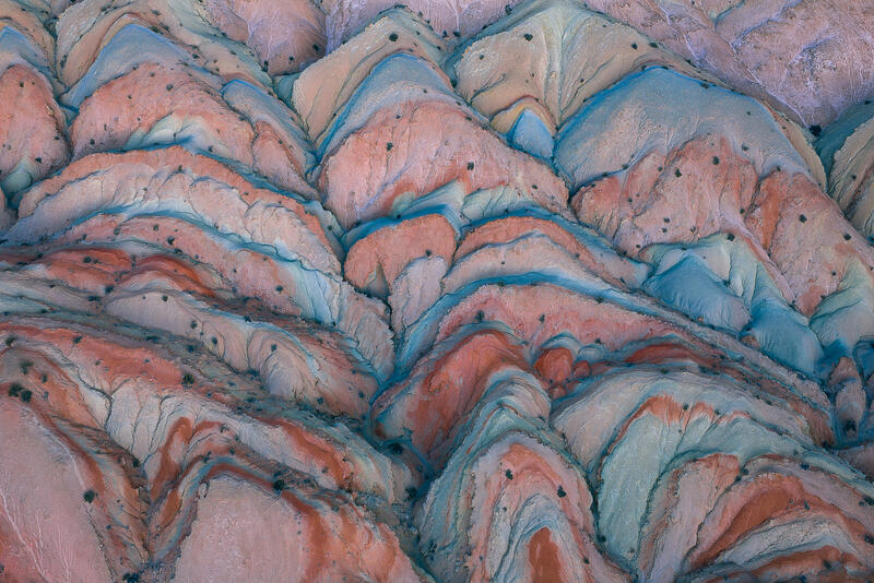 Pastel red and turquoise layered badlands hills in Utah desert.