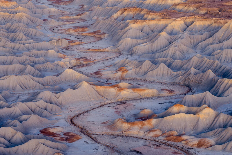 Winding desert wash through pale clay hills in Utah badlands.