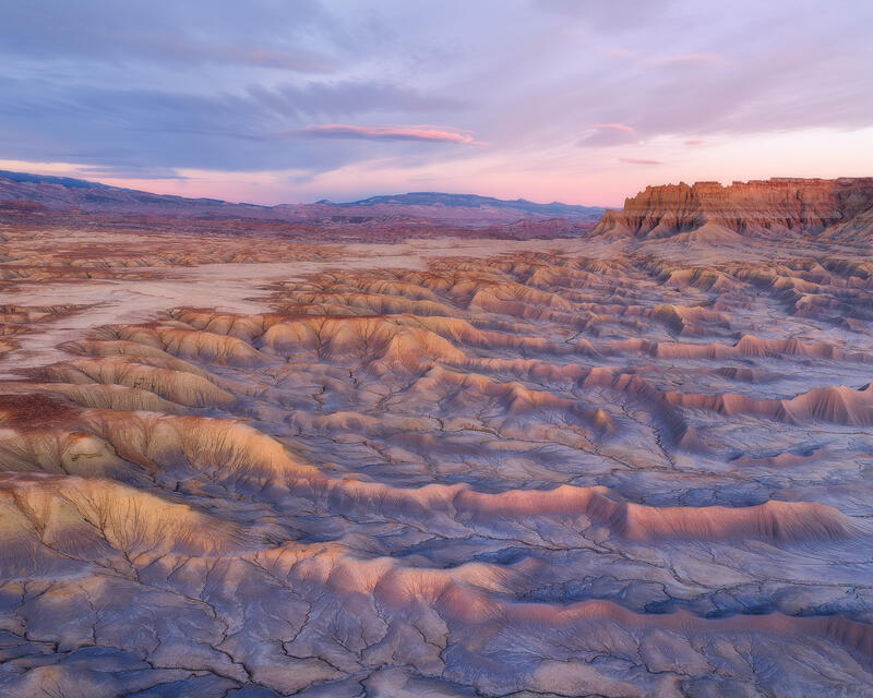 Pastel-toned Utah badlands glow beneath a tranquil dusk sky in this serene Colorado Plateau landscape.