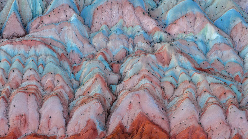 Pastel-colored badlands ripple across Utah’s desert in soft, abstract aerial patterns.