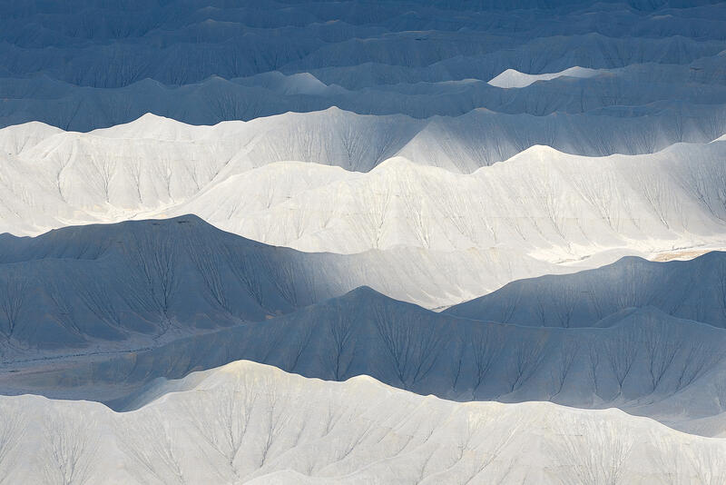 White and blue badlands form soft, wave-like patterns of light and shadow across Utah’s desert.