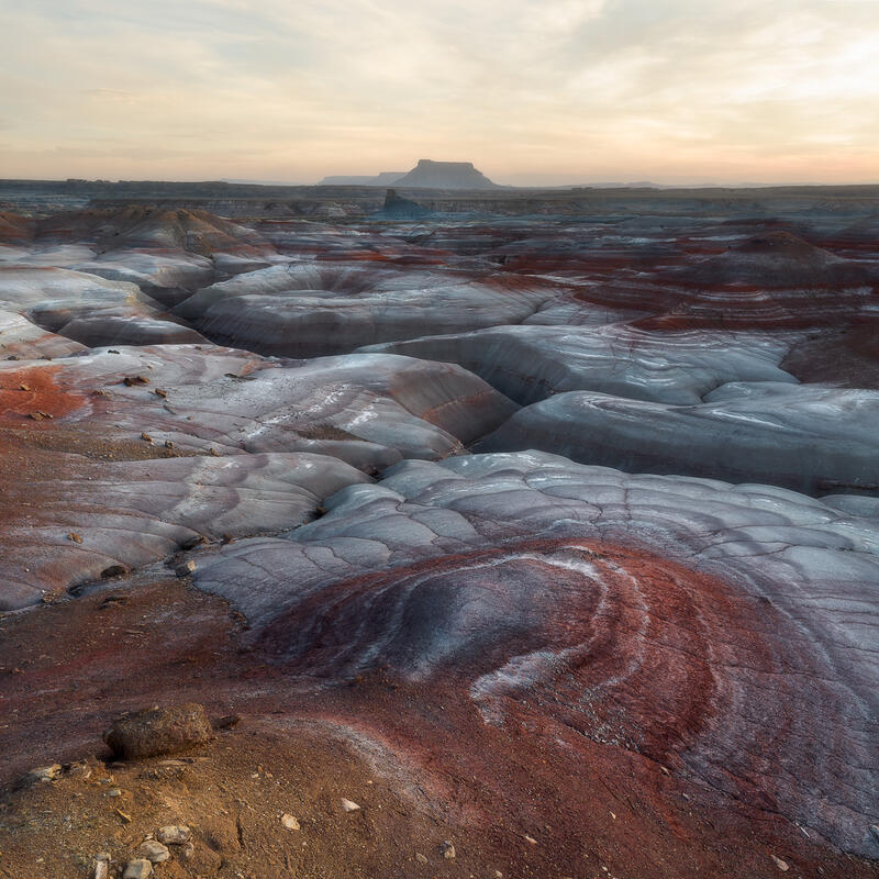Winding erosion channels flow through blue-gray Utah badlands.