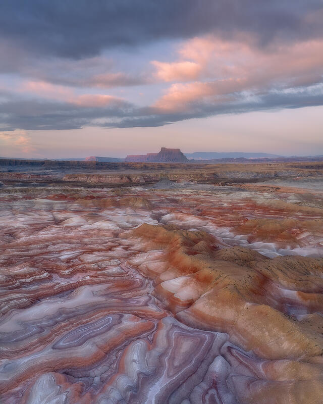 Pastel clouds and layered badlands create a soft, dreamlike desert scene in Utah.