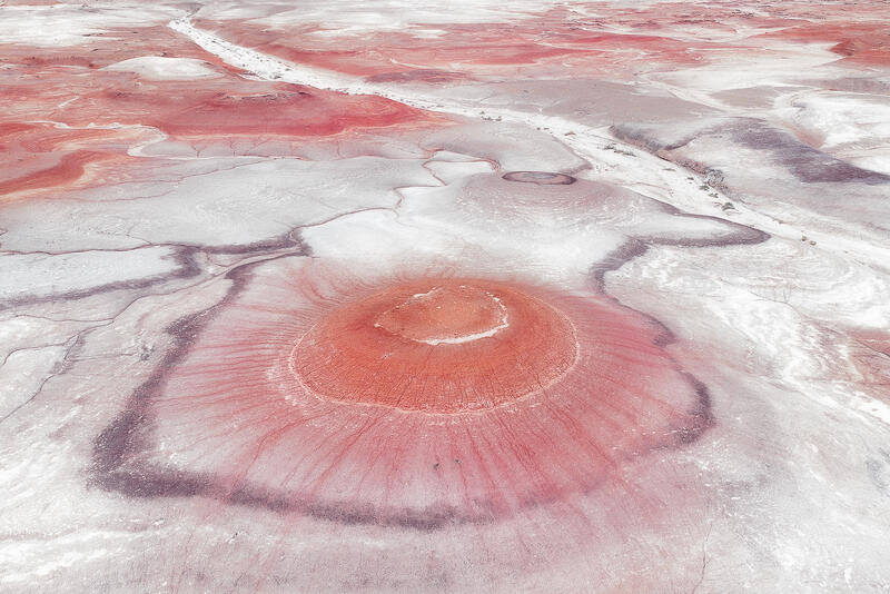 A crimson desert mound radiates outward like a natural bloom in Utah’s badlands.