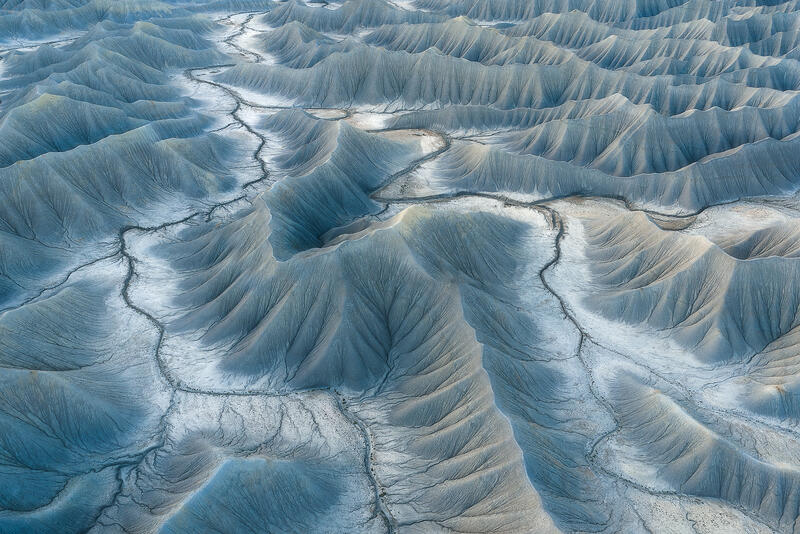 Soft blue ridges form rhythmic layers across Utah badlands at dawn.