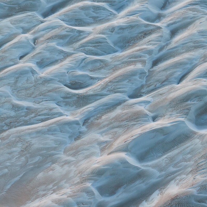 An aerial abstract of softly sculpted sand dunes with flowing textures in the Australian desert.
