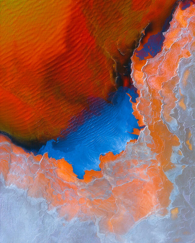 An abstract aerial of vivid mineral colors and flowing textures blending into a dramatic natural composition.