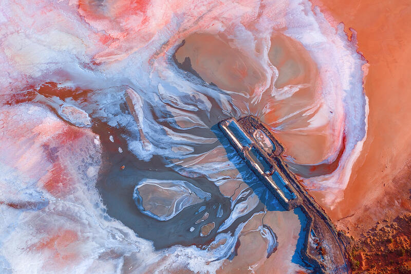 An abstract aerial of mineral-rich waterways and colorful salt formations flowing together like liquid paint across the Australian landscape.