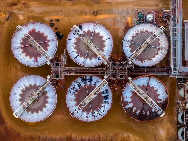 An abstract aerial view of gold refinery equipment forming geometric industrial patterns across the landscape.
