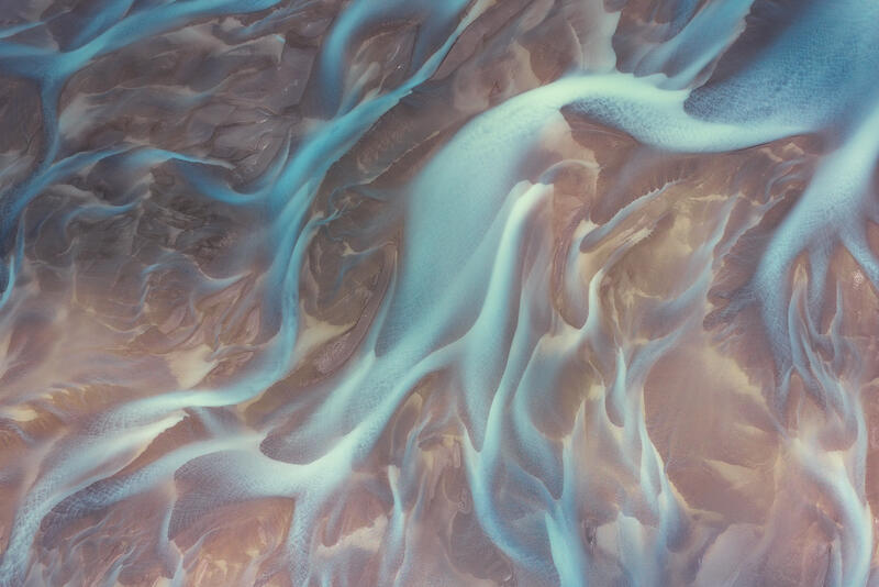 Pastel aerial abstract of turquoise glacial rivers flowing across volcanic sands in Iceland