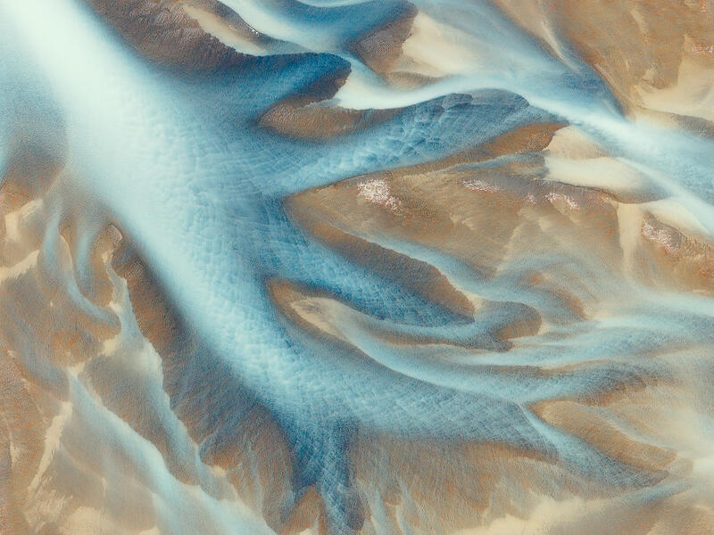 Turquoise glacial channels sweep across Iceland's volcanic landscape, forming an elegant abstract reminiscent of a manta ray in motion.