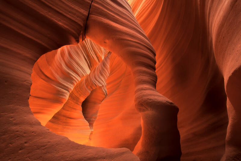 A sculpted sandstone arch frames the glowing beauty of an ancient slot canyon.