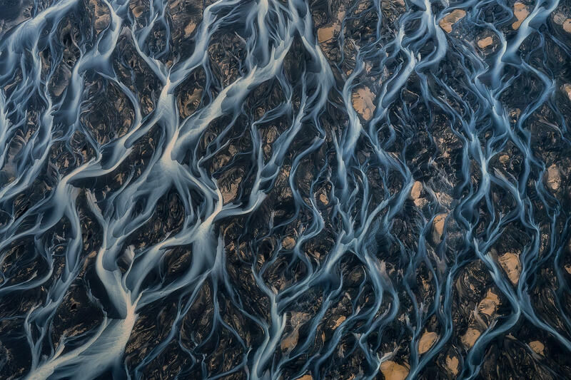 Delicate braided rivers create lace-like patterns across Iceland's volcanic landscape.
