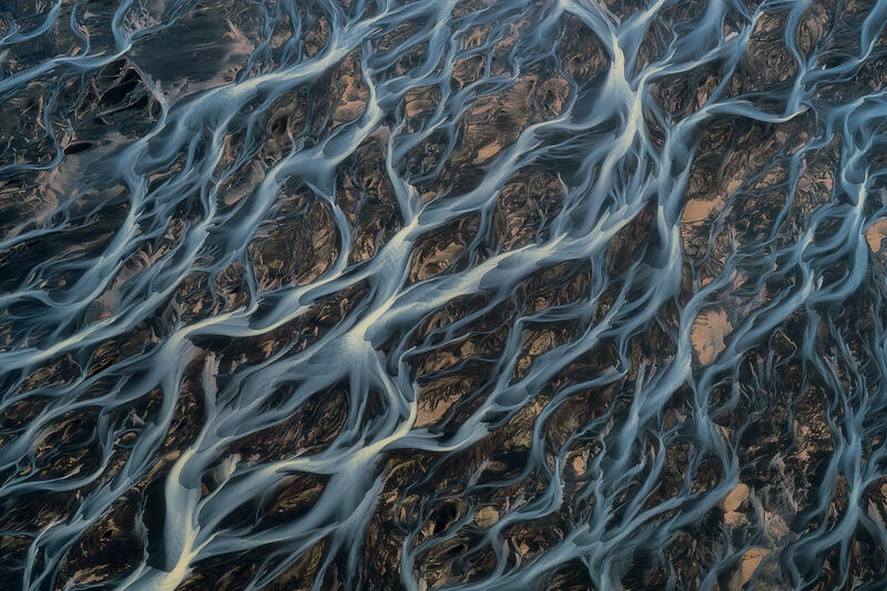 Aerial abstract of branching braided glacial rivers crossing volcanic plains in Iceland.
