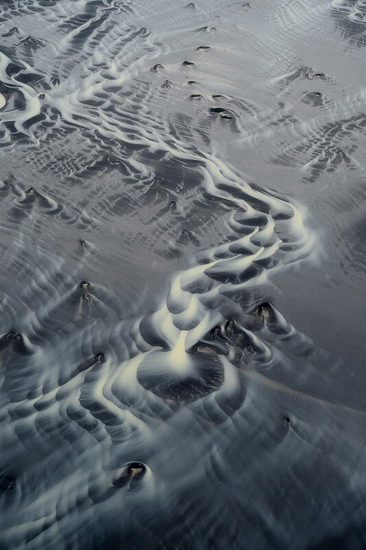 single luminous glacial channel winds gracefully across Iceland's volcanic sands.
