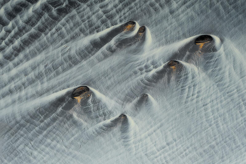 Wind-carved volcanic dunes rise like silent guardians across Iceland's sculpted sands.