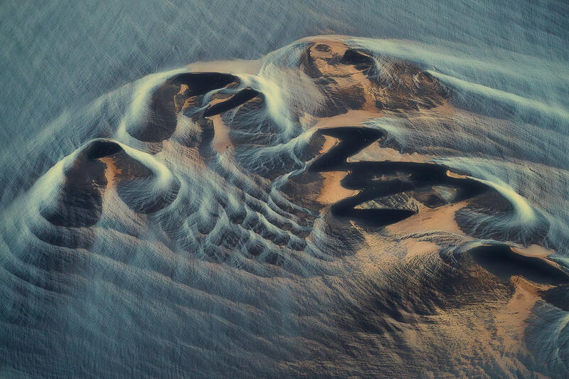 Ancient-looking landforms emerge from Iceland's braided river plains in a striking aerial abstract.
