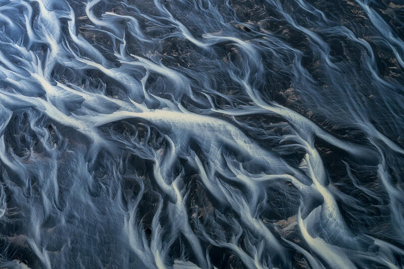 Silver glacial rivers weave intricate patterns across Iceland's volcanic floodplain.