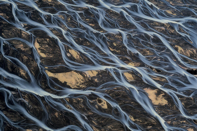 An intricate network of glacier-fed rivers flows like living veins across Iceland's volcanic landscape.