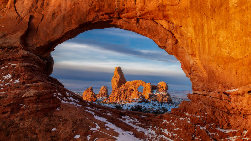 Turret Arch framed by a sandstone arch with snow in Arches National Park, Utah.
