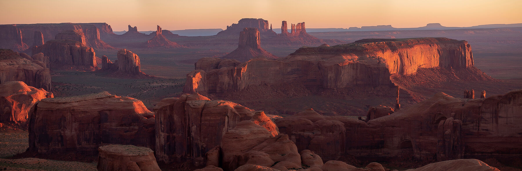 Monument Valley Sunrise Iconic desert scene of monument valley with buttes and mesas as the sun rise side lights the scene from the right side.