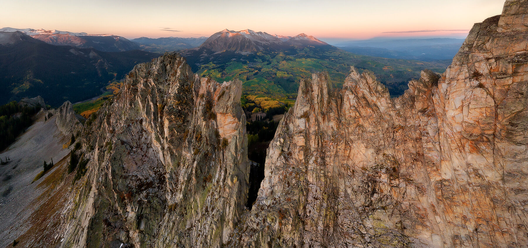 Mountains in the background are hit by the sunrise while a wall of jagged mountains frames the front of the image.