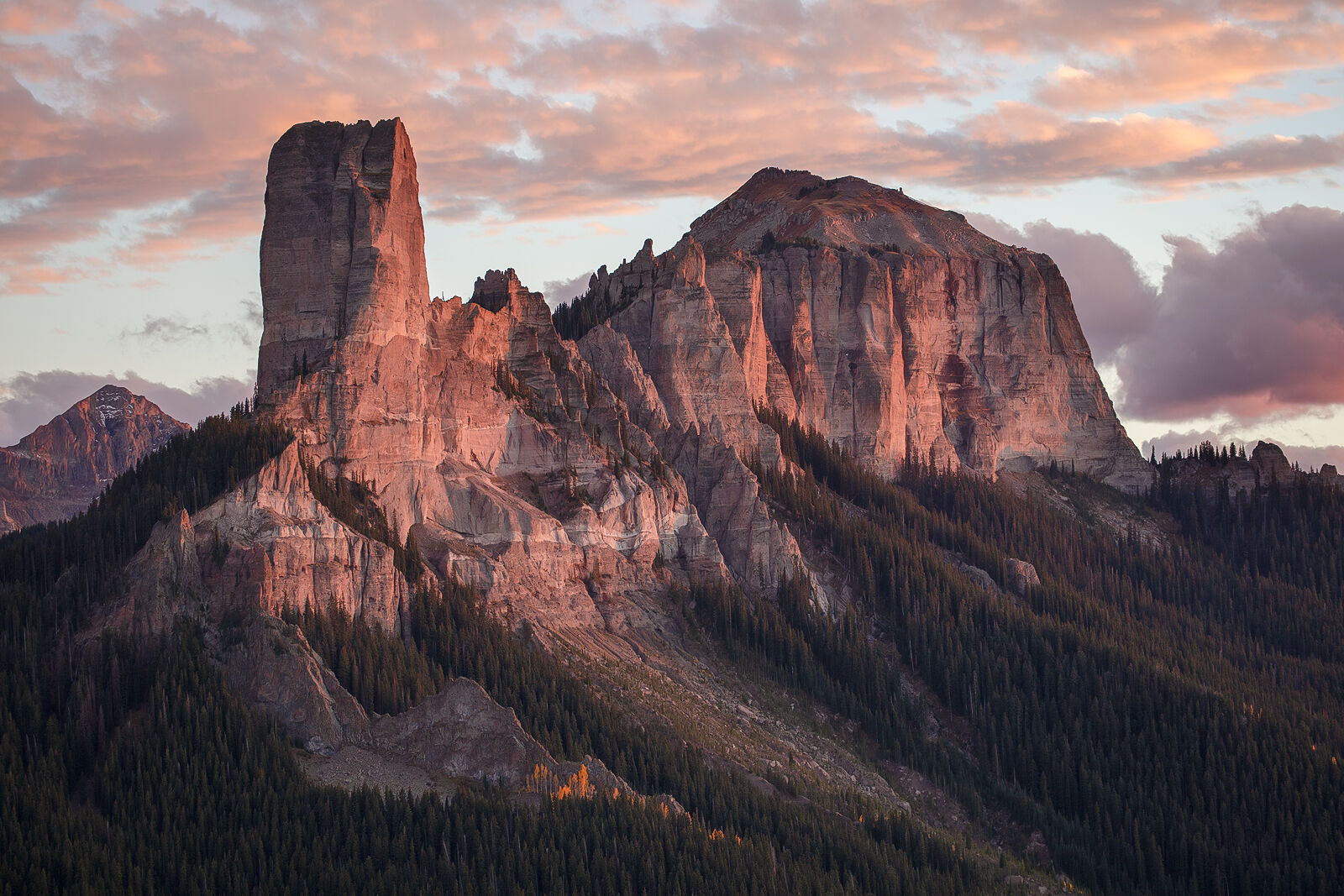 Chimney Rockin Reds Tall, columnar mountain peak with sunlight on it and pink clouds at sunset giving the entire image a reddish hue.