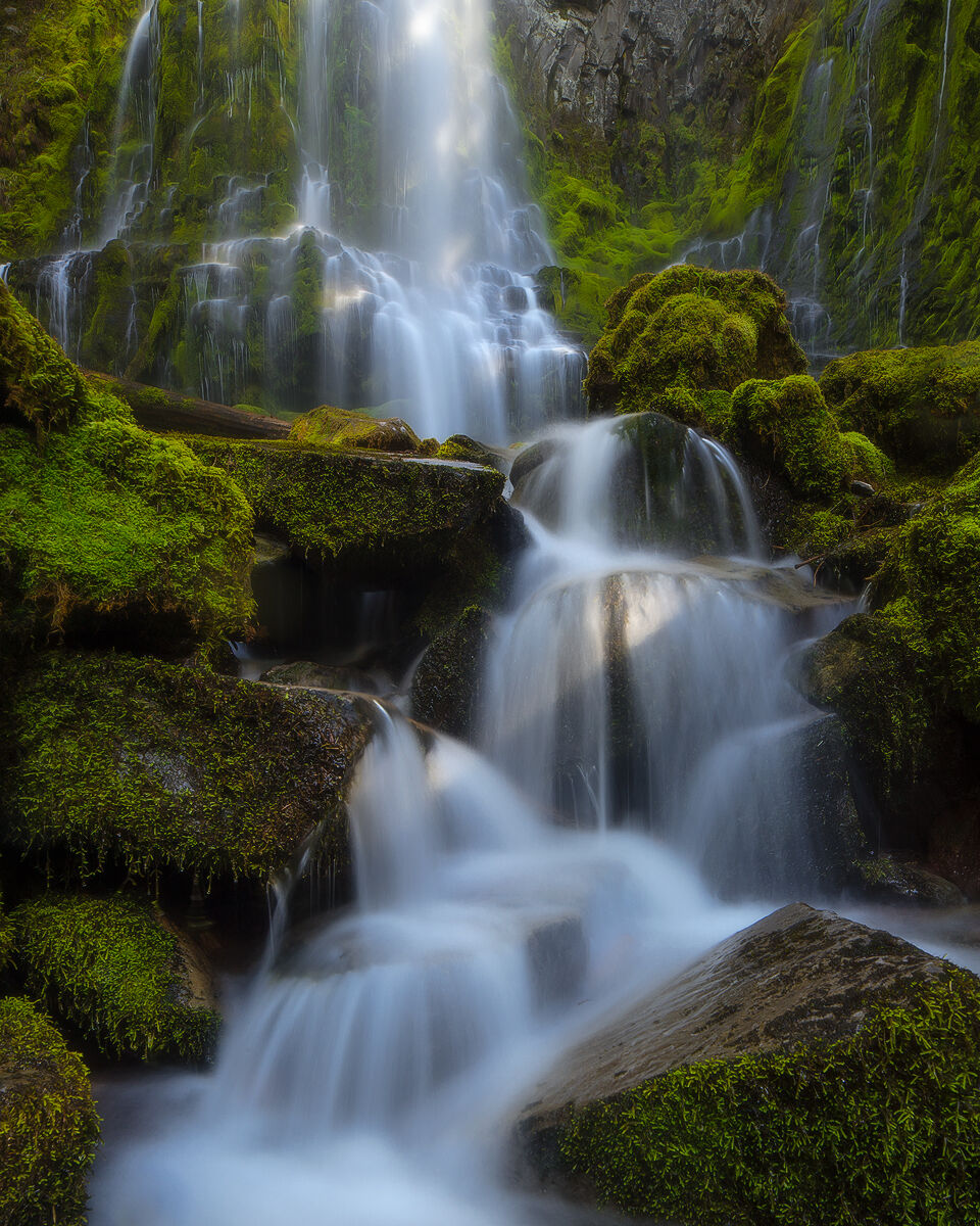 A waterfall has many levels that turn through the mossy covered rocks in a river gorge.